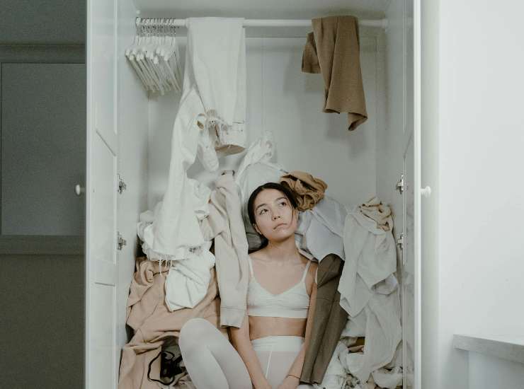 ragazza in armadio sommersa dagli abiti